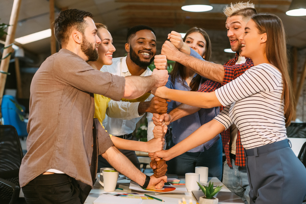 Young business team building tower from fists, celebrating success